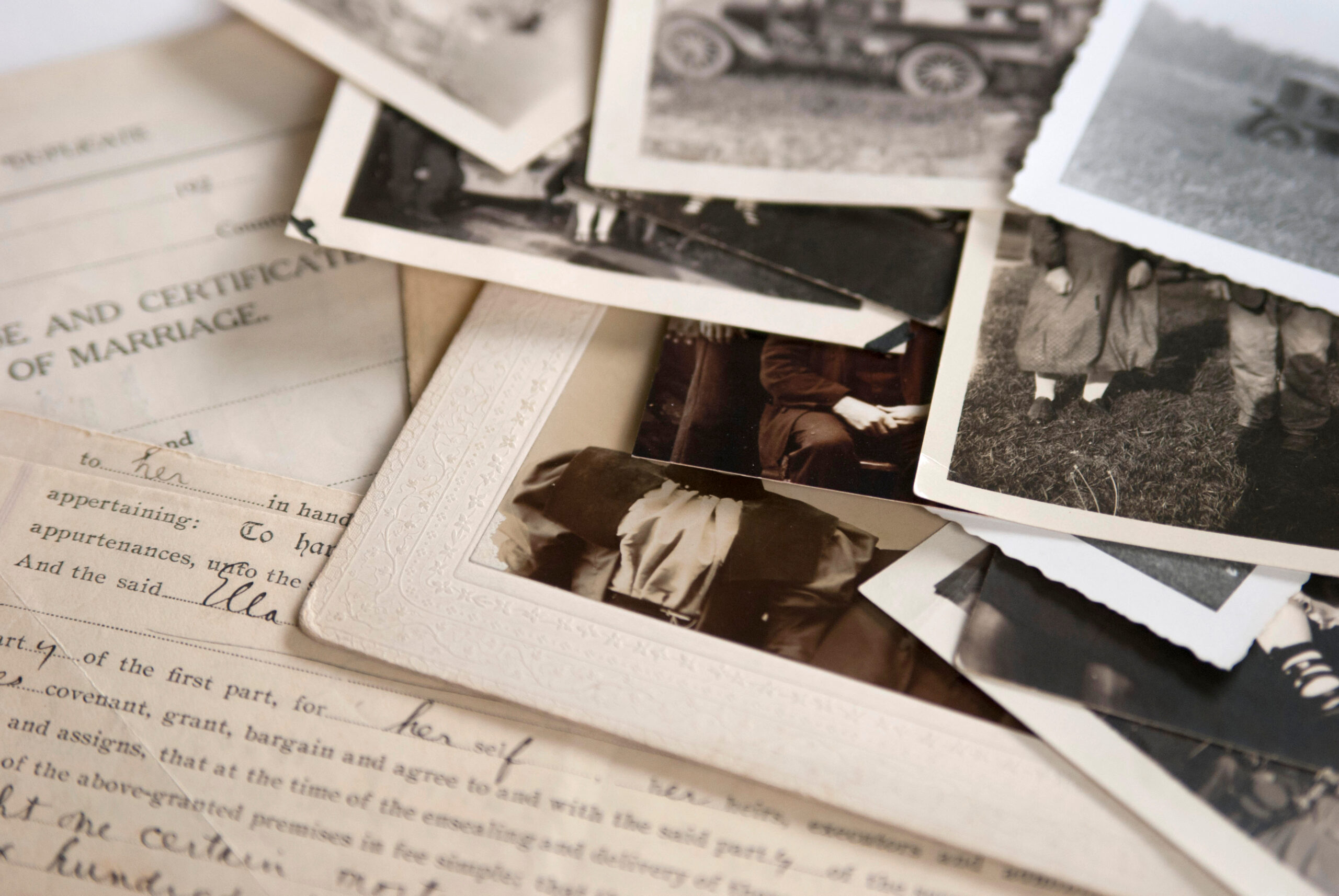 Old family photographs and a vintage marriage certificate spread on a table